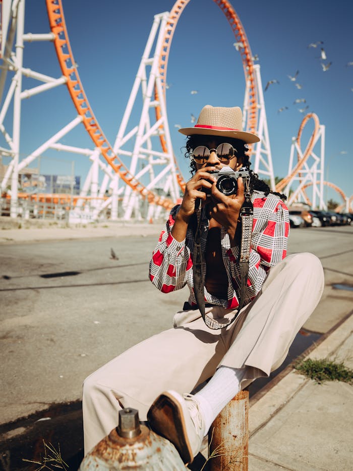 Stylish man with a camera captures moments at the iconic Coney Island amusement park.